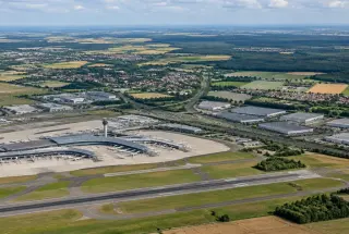 Vue aérienne réaliste de l’aéroport Paris-Charles de Gaulle entouré de communes, de routes, de zones d’activités et de terres agricoles du Grand Roissy.